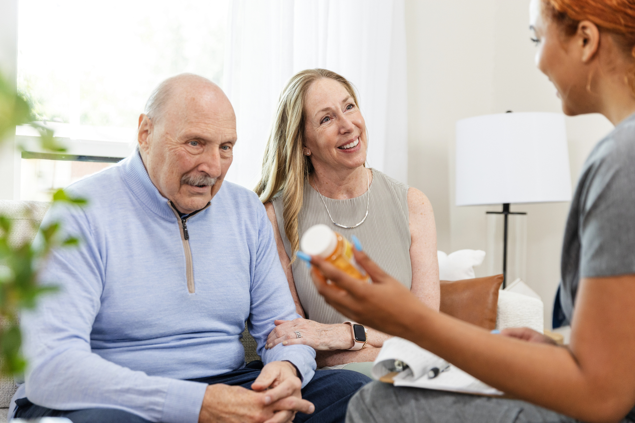 Woman and nurse discuss medications while senior dad looks away